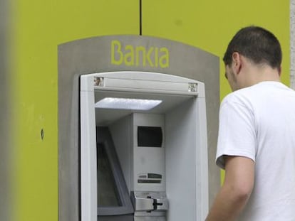 Un hombre saca dinero de un cajero automático de Bankia.