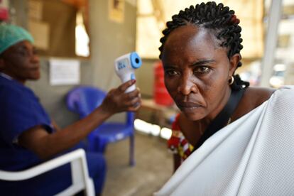Una trabajadora de salud verifica la temperatura de una mujer como parte de la prueba de detección del ébola, al ingresar al Hospital General en Goma (República Democrática del Congo).