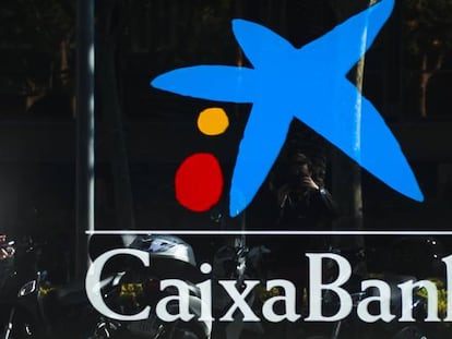 Dos personas pasando por delante de una oficina de CaixaBank en Barcelona