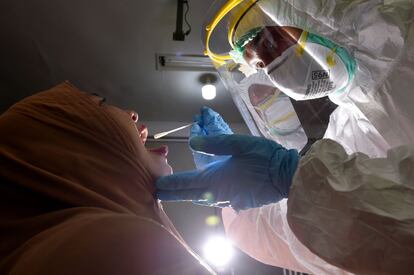 Un enfermero, con equipo de protección, toma una muestra a una paciente para la prueba de coronavirus, en Banda Aceh (Indonesia).