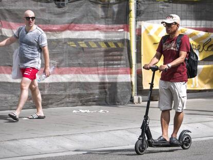 Un hombre circula con un patinete eléctrico por Sants, Barcelona.
