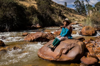 María Rodríguez Macedo toma el sol frente a un cauce del Río Negro, en la comunidad de Cordillera Blanca (Perú).