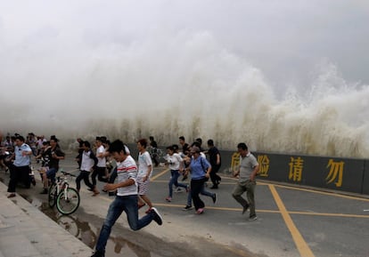 Varias personas huyen de las olas causadas por una marea a las orillas del río Qiantang, en Hangzhou, provincia de Zhejiang (China). 
