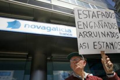 Un hombre sostiene una pancarta, durante la concentración de afectados por las acciones preferentes y subordinadas de Novagalicia Banco, en La Coruña. EFE/Archivo