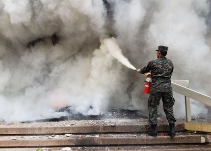 Un soldado intenta apagar con un extintor el incendio.
