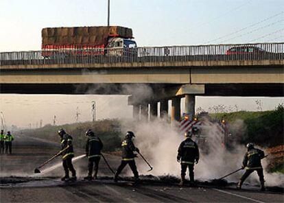 Los bomberos limpian las barricadas instaladas ayer por los trabajadores de los astilleros en Sevilla.