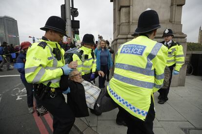 Tres oficiales de policía retiran a un manifestante por el clima del puente Lambeth en el centro de Londres.