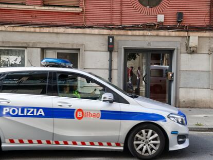 Agentes de la policía local de Bilbao pasan por delante del portal del suceso en el barrio de Santutxu, este viernes.