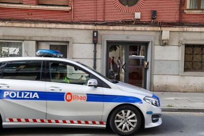 Agentes de la policía local de Bilbao pasan por delante del portal del suceso en el barrio de Santutxu, este viernes.