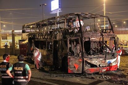 Os policiais ao lado dos restos do ônibus em chamas. Este é um dos piores acidentes em massa registrado na capital peruana nas duas últimas décadas.