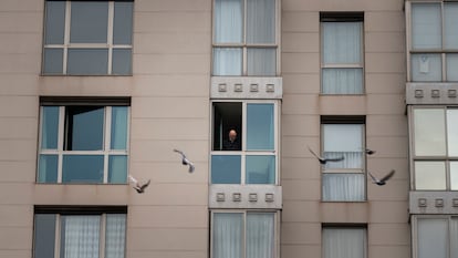 Un home mira des de la seva finestra en un edifici de Barcelona.