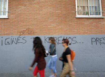 Tres mujeres pasan junto a una pared con una pintada contra el jefe de la Policía Local de Coslada.