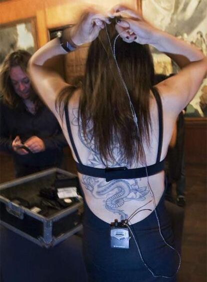 En primer plano, la espalda tatuada de Eva Amaral mientras se coloca en los camerinos el sistema de audición de directo. Quedan pocos minutos para subir al escenario.