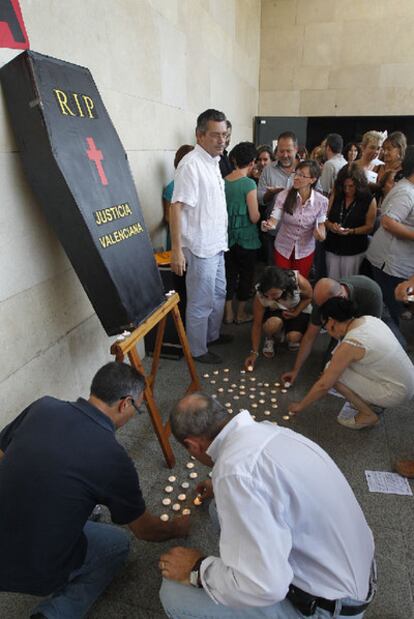 Los trabajadores depositan velas en una representación del entierro de la Justicia.