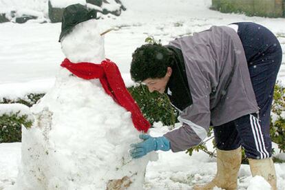 Una vecina hace un muñeco de nieve esta mañana en el alto de Cedeiro, entre Ferrol y Ortigueira (Galicia).