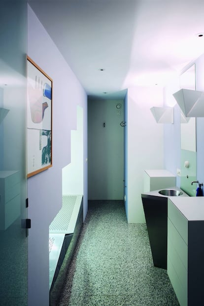 El baño tiene los lavabos triangulares, suelo de granito y hasta un solárium (izda.) que sirve de almacenaje.