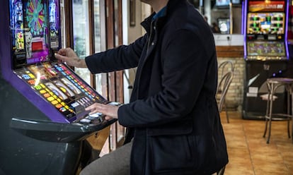 Un hombre echa una moneda a una máquina tragaperras en un bar de Valencia.