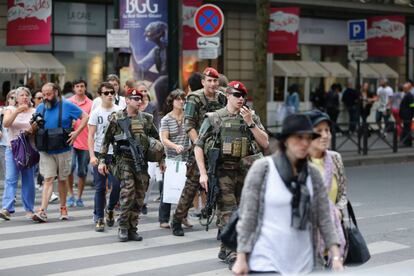 Una patrulla militar cruza una calle de París junto a varios ciudadanos.