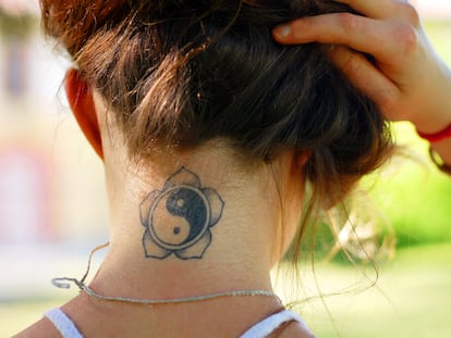 Una joven muestra su tatuaje en la nuca.