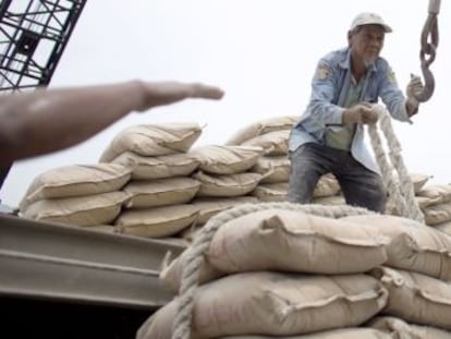 Trabajadores cargan sacos de cemento en un barco.