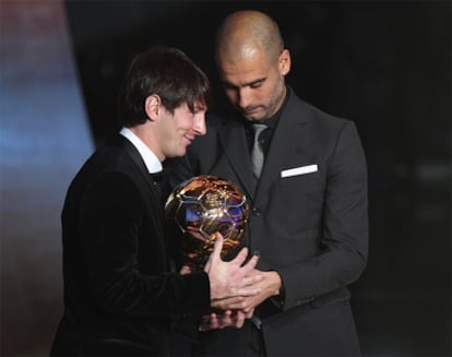 El futbolista argentino del Barcelona, Lionel Messi, recibe el Balón de Oro de las manos de su entrenador, Pep Guardiola.