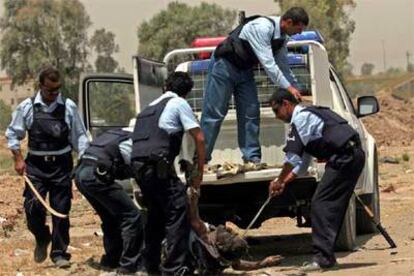 La policía iraquí arrastra el cuerpo de un hombre que hizo explotar su coche al paso de un convoy.