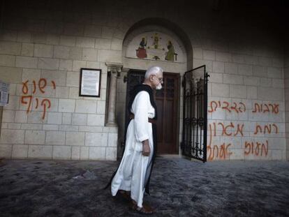 Un monje camina frente a las pintadas en la fachada del monasterio &quot;Jes&uacute;s es un mono&quot; y los nombres de dos asentamientos jud&iacute;os.