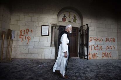 Un monje camina frente a las pintadas en la fachada del monasterio &quot;Jes&uacute;s es un mono&quot; y los nombres de dos asentamientos jud&iacute;os.