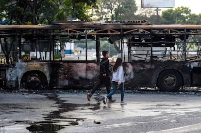 Dos jóvenes pasan frente a un autobús incendiado en una calle de la capital del país sudamericano.