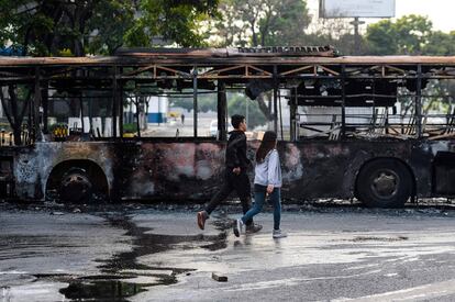 Dos jóvenes pasan frente a un autobús incendiado en una calle de la capital del país sudamericano.