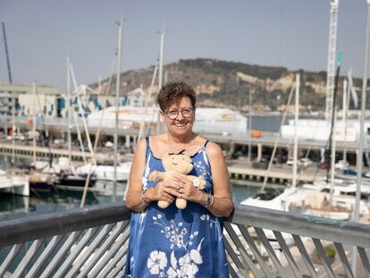 Maria Rosa Madonar, voluntaria de la Copa América de Vela que se celebrará en Barcelona en 2024, fotografiada frente a la base del equipo italiano Luna Rossa en el puerto de Barcelona junto a un muñeco del Cobi, icono de los Juegos del 92.