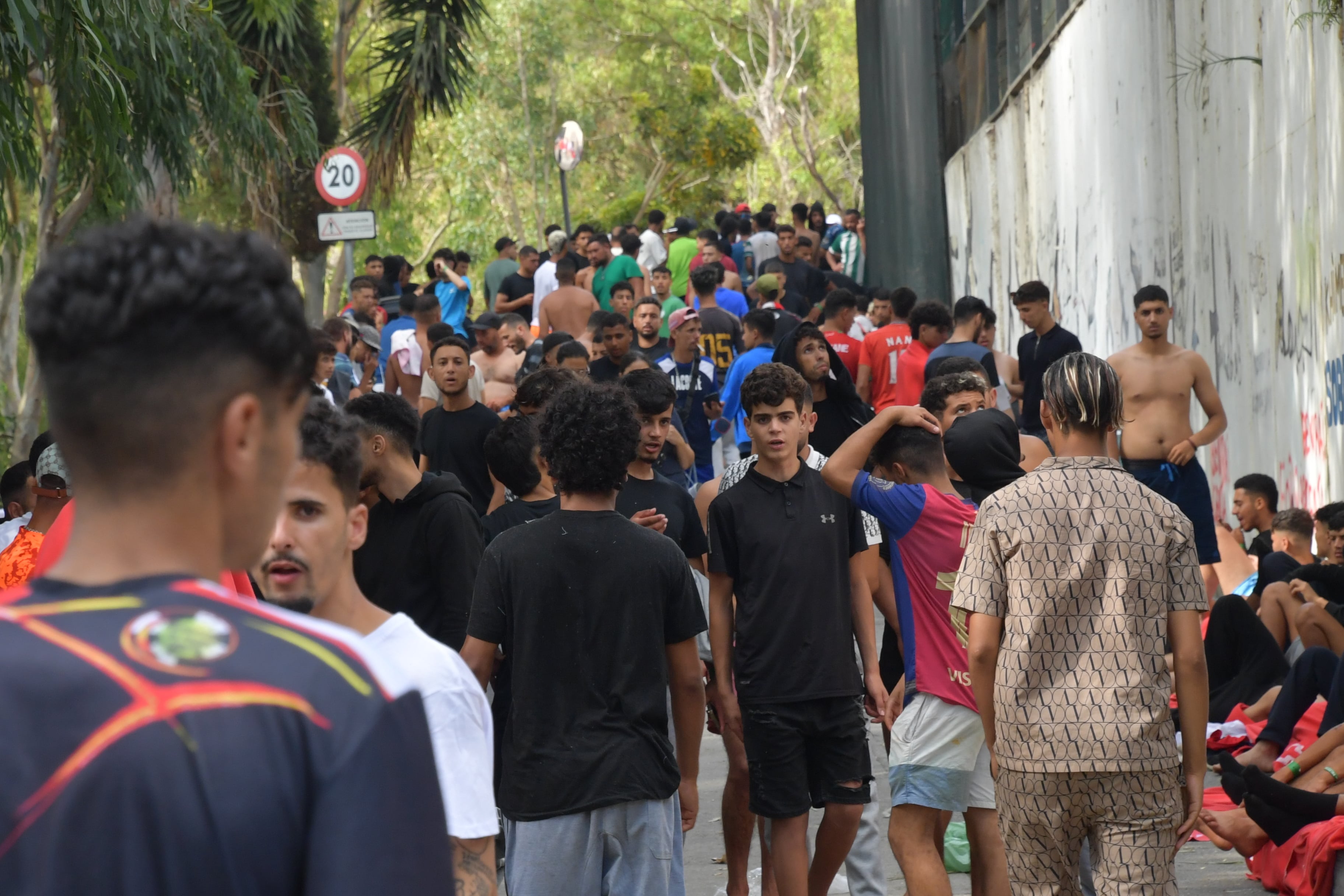 Migrantes marroquíes y argelinos aguardan a las puertas del CETI de Ceuta, este jueves.