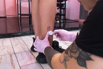 Una tatuadora del Coven Tattoo Studio pinta el diseño que tatuará en la pierna de Alexis Laube.