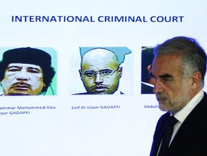 El fiscal Moreno Ocampo juto a las fotos de Gadafi y su hijo Saif.