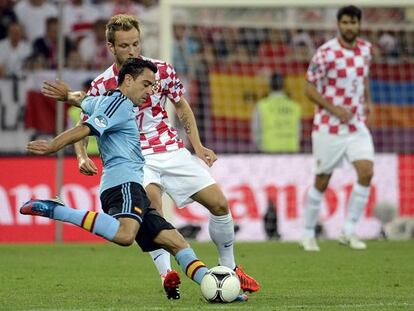 Xavi golpea el balón ante Rakitic durante el partido Croacia-España.