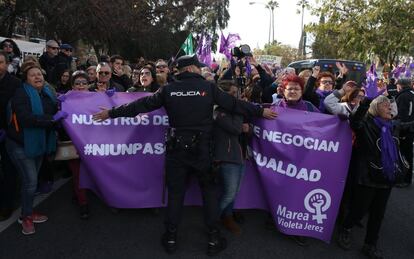 Un policía trata de detener el avance de la protesta feminista frente al Parlamento de Andalucía.