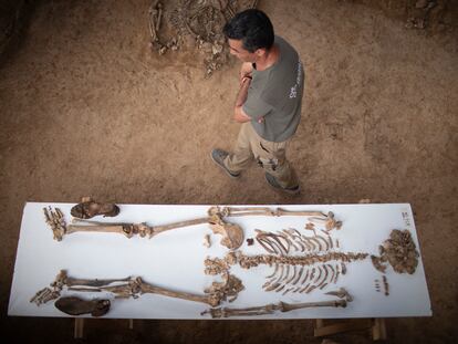 Uno de los técnicos que trabaja en la fosa de Pico Reja pasa junto a una mesa con los restos y enseres personales de uno de los integrantes de la Columna Minera.