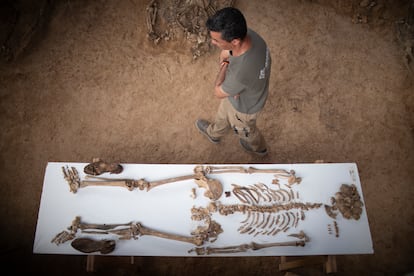 Uno de los técnicos que trabaja en la fosa de Pico Reja pasa junto a una mesa con los restos y enseres personales de uno de los integrantes de la Columna Minera.