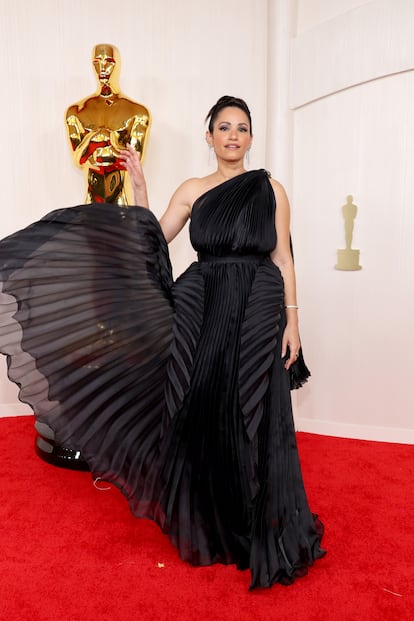 La actriz Tiffany Smith, jugando para la fotografía con la falda plisada de su vestido negro de escote asimétrico.