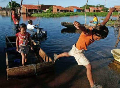 Un niño salta desde un bote en una calle inundada por las lluvias torrenciales en la localidad boliviana de Trinidad.