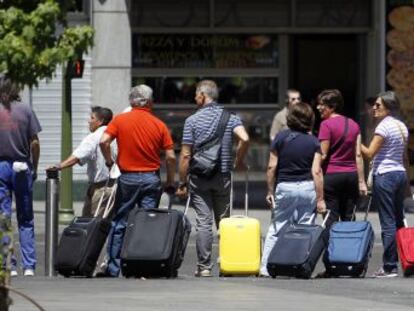 Un grupo de turistas tira de sus maletas en un paso de peatones de la Gran V&iacute;a de Madrid.