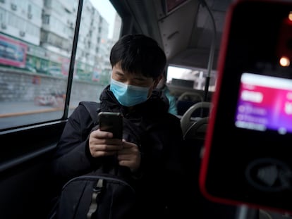 Passageiro de ônibus olha o celular em Pequim.