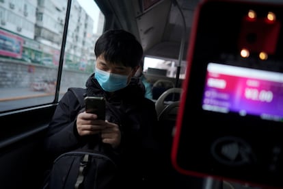 Passageiro de ônibus olha o celular em Pequim.