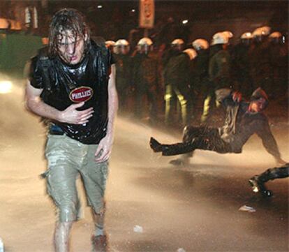 Un detractor de Bush corre a ponerse a salvo del cañón de agua que la policía utilizó anoche al este de Berlín.