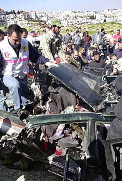 Sanitarios palestinos revisan un coche destruido por un misil israelí en Ramala.