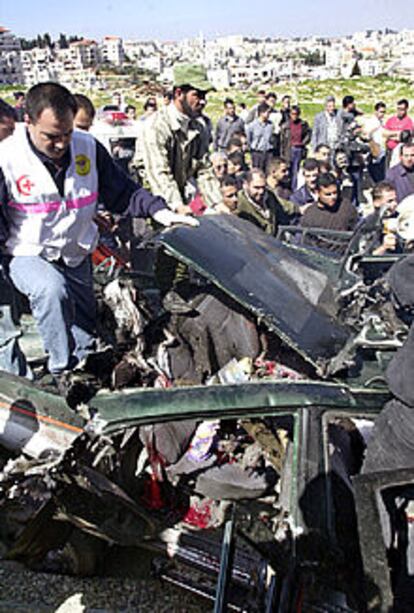 Sanitarios palestinos revisan un coche destruido por un misil israelí en Ramala.