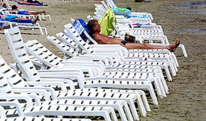 Un turista toma el sol en la playa d&#39;en Bossa, de Ibiza.