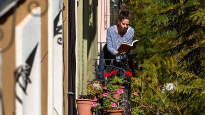 Una mujer lee un libro en el balcón de su casa, durante el confinamiento, en Barcelona.