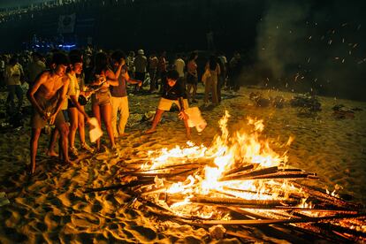 Un grupo de adolescentes quema los exámenes y apuntes de la EBAU en una de las hogueras de la playa de Riazor, A Coruña.  