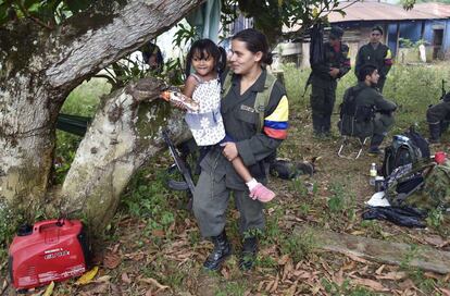 A member of the Revolutionary Armed Forces of Colombia (FARC) holds the daughter of a mate during a visit of their relatives, at a camp in the Colombian mountains on February 18, 2016. Many of these women are willing to be reunited with the children they gave birth and then left under protection of relatives or farmers, whenever the imminent peace agreement puts an end to the country's internal conflict. AFP PHOTO / LUIS ACOSTA